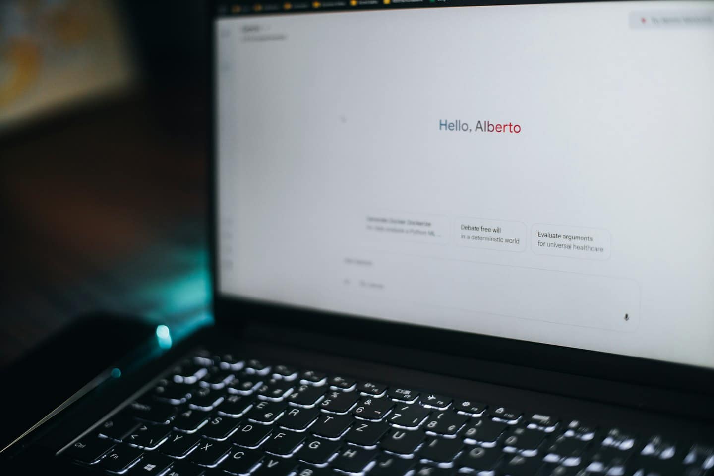 Schermo di un laptop mostra un'interfaccia AI con un saluto e dei prompt.